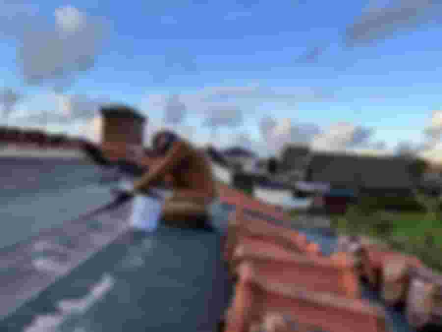 Person arbetar på takprojekt under helgen, med utsikt över hus.