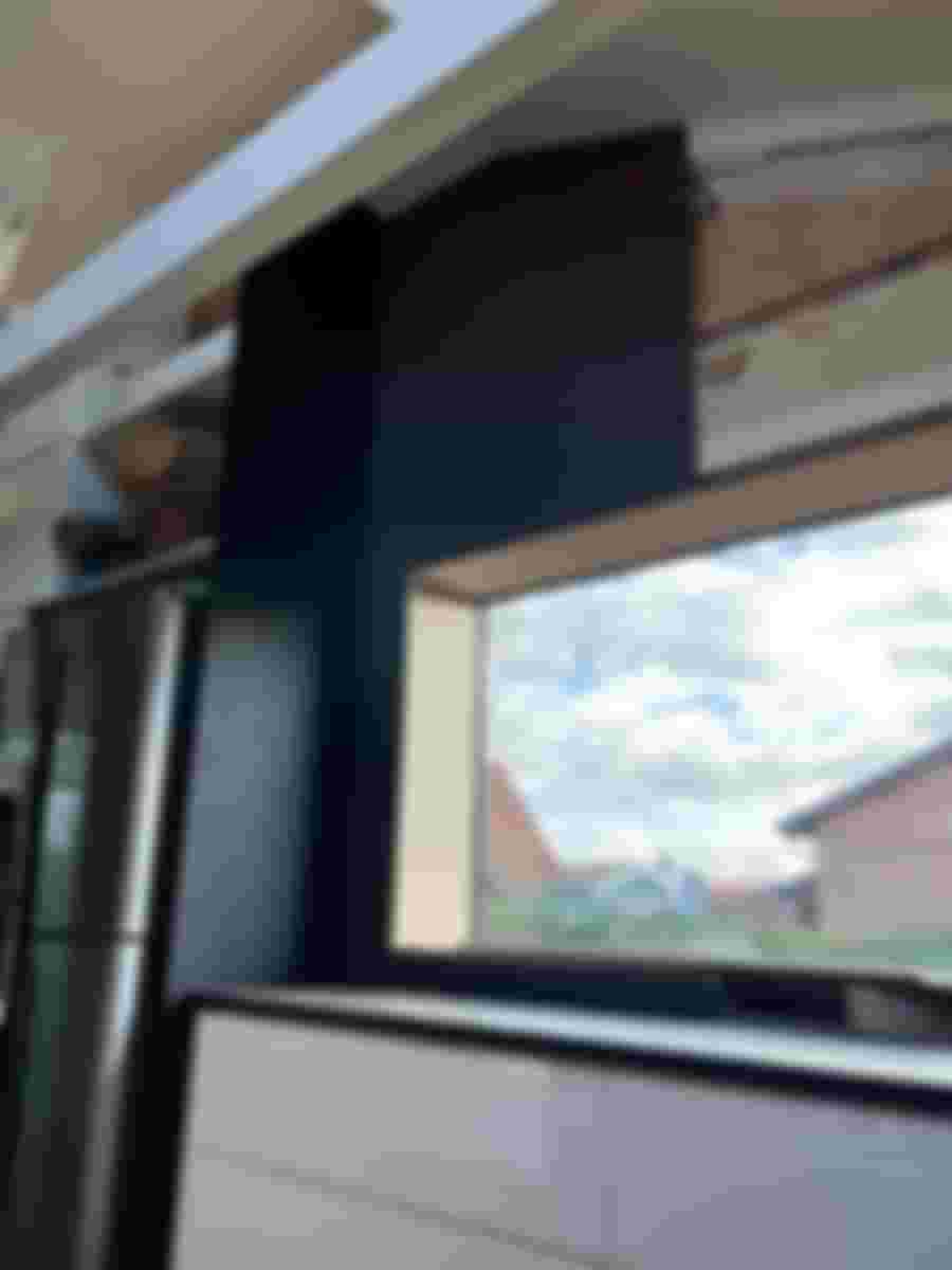 Kök med stilren svart vägg och stort fönster som släpper in naturligt ljus, vilket ger en modern och luftig känsla.