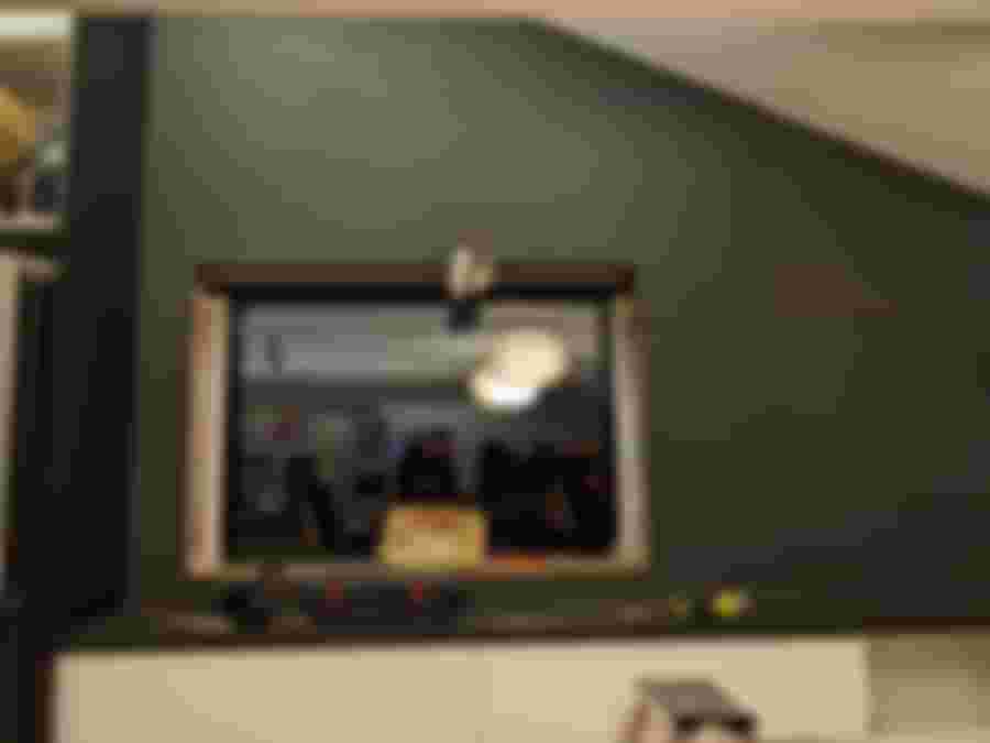 Ett halvrenoverat rum med ett stort fönster, två pendellampor och verktyg på en bänk, vilket skapar en modern, öppen känsla.