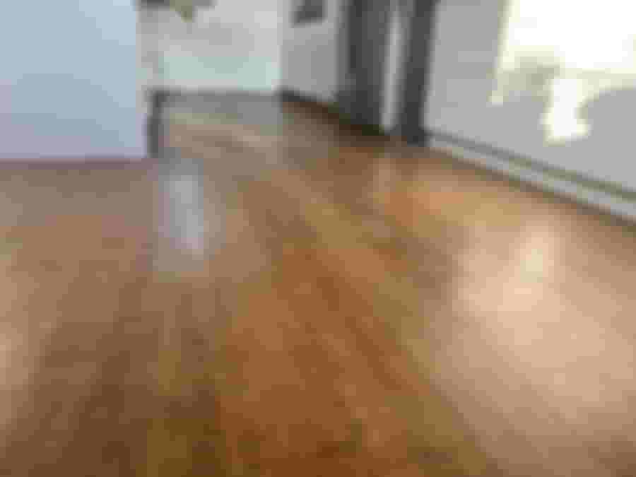 En ljus och modern köksmiljö med ett snyggt, brunaktigt golv av laminat. Reflexer från fönstret skapar en varm atmosfär.