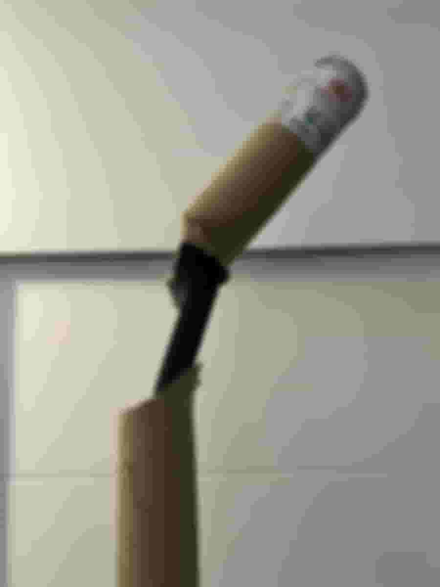 En trasig kartongrulle med en böjd svart stång syns mot en vit vägg, antyder en leveransskada.