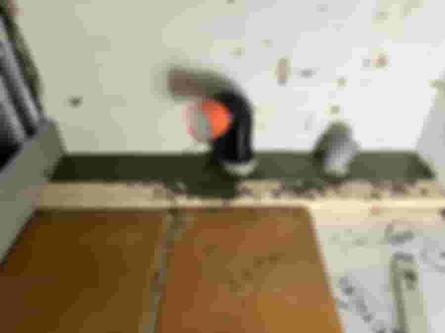 Renoveringsprojekt med installation av avloppsrör i betongvägg. Synliga byggmaterial inkluderar trä, betong och rördelar. Arbetsplatsen visar pågående arbete.