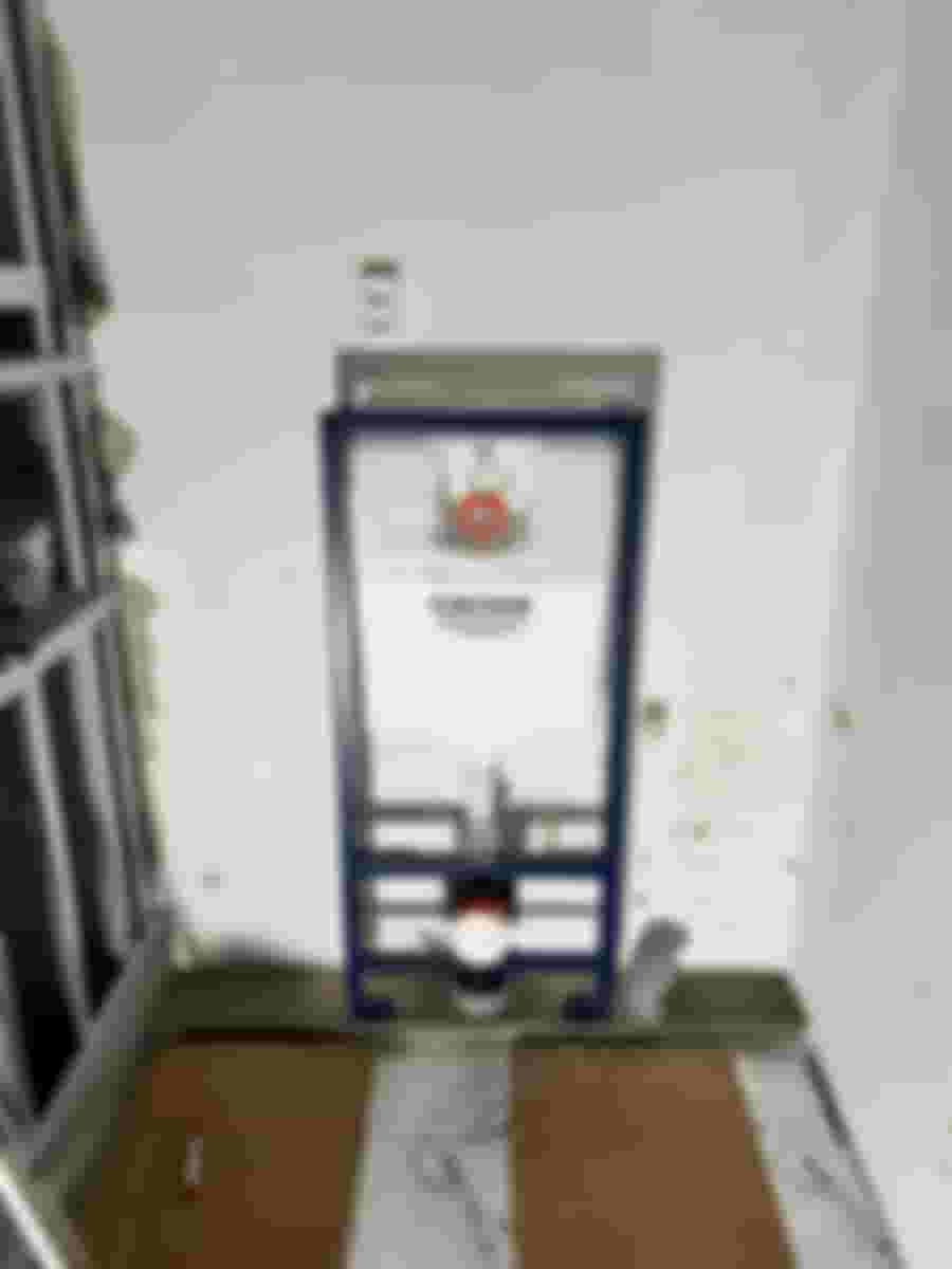 Väggmonterad toalettinstallation med Grohe-cistern under renovering. Omgiven av byggmaterial och verktyg. Förberedelse för kakelsättning och rördragning.