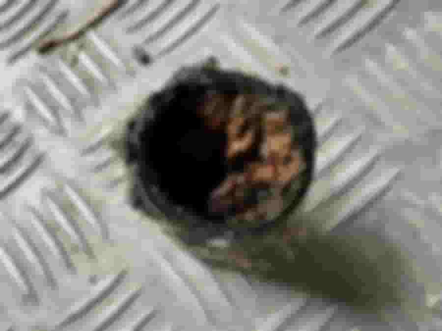 En rostig, sliten koppling på en räfflad metallplatta, vilket antyder behov av reparation eller utbyte under renoveringsarbetet.