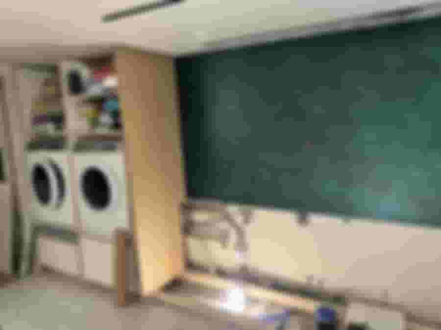 Lugnare renoveringsutrymme med grön vägg och tvättmaskiner.