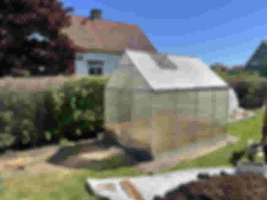 Växthuset står på en ram av gamla stenplattor i trädgården.