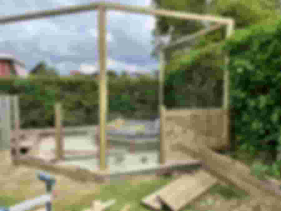 Badtunna omgiven av trästaket och glasparti, renovering pågår.