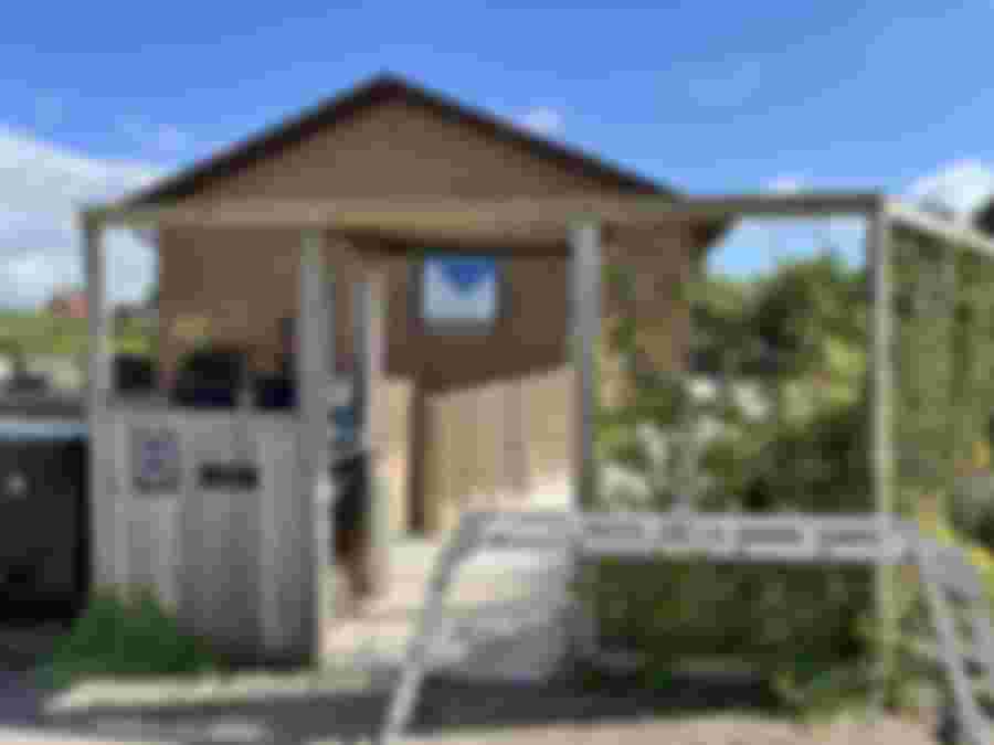 Entré till ett hus med träveranda och grönska.