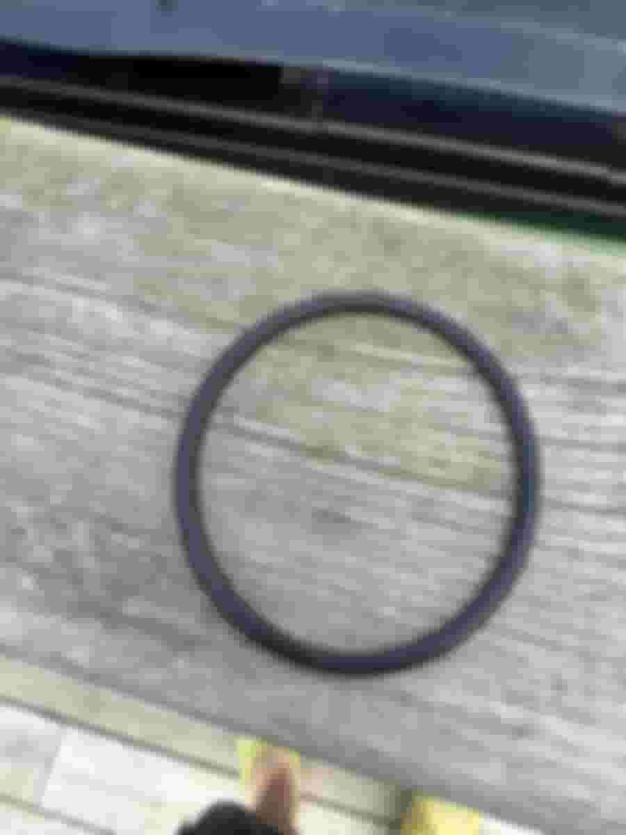 En svart gummiring ligger på en träyta, en del av badtunnans kopplingar för att åtgärda vattennivån.